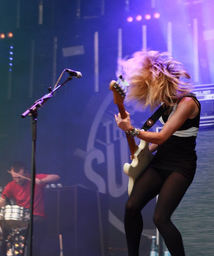 The Subways' bassist in joyful movement, her hair covering her face